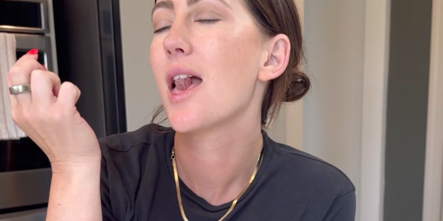 Jar of Ease strawberry hibiscus gummies on a pink background surrounded by strawberries and hibiscus flowers