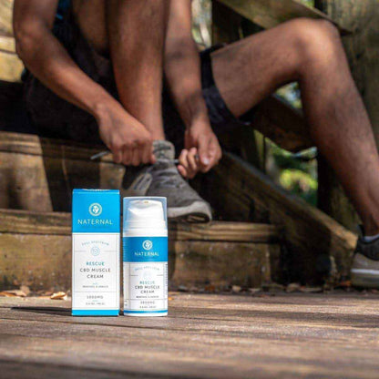 Man on a wooden deck with a bottle of Rescue CBD Muscle Cream 1000mg next to him